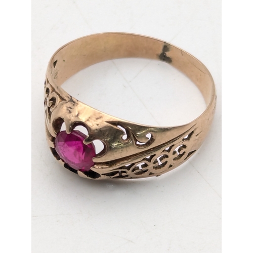 80 - A ruby and rose gold ring tested as 9ct having pierced design to the shoulders on a tapering shank s... 