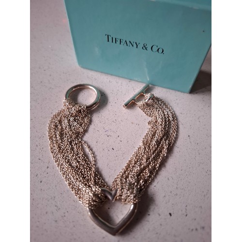Tiffany & Co- A multi-strand silver mesh and open heart bracelet 21g, max wrist size 15cm, having a toggle fastening with branded turquoise pouch and box and Tiffany & Co 925 stamped to the bar. Location:Cab1
If there is no condition report, please request