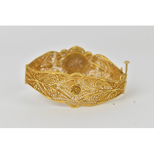 2 - An 18ct gold filigree sapphire, ruby and pearl bracelet, the ornate hinged panels decorated with scr... 