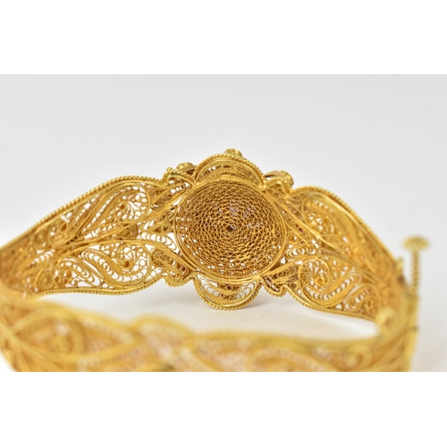 2 - An 18ct gold filigree sapphire, ruby and pearl bracelet, the ornate hinged panels decorated with scr... 