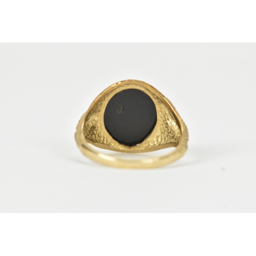 58 - A 9ct gold snake-set onyx ring, the oval onyx panel mounted within a textured bezel, the curling ser... 
