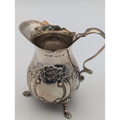 12 - A Victorian silver cream jug having floral embossed decoration hallmarked London 1898 together with ... 