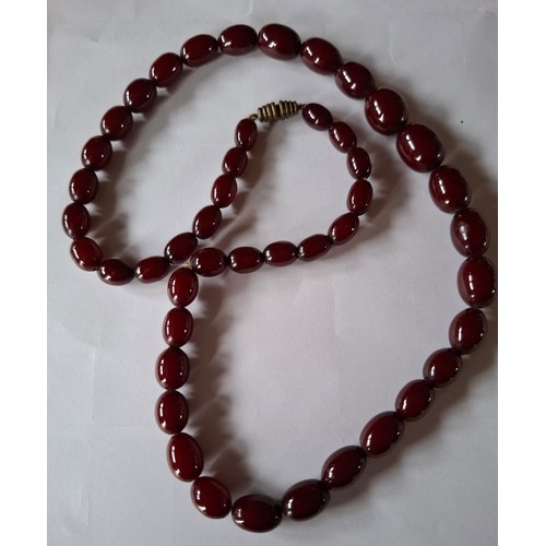 49 - A vintage string of cherry coloured beads comprising 46 oval graduating beads, measures approx 50cm ... 