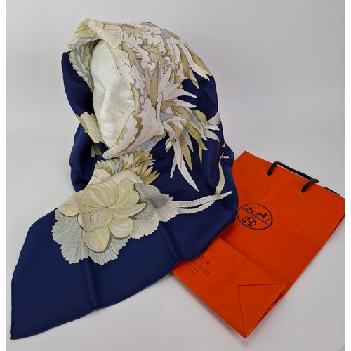 15 - Hermes- A 1990's Tahiti by Cathy Latham silk scarf having a navy ground with gold, cream and grey fl... 