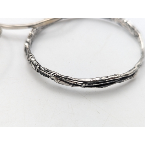 33 - A collection of silver bangles to include examples from Mexico, a Navajo style cuff bracelet set wit... 