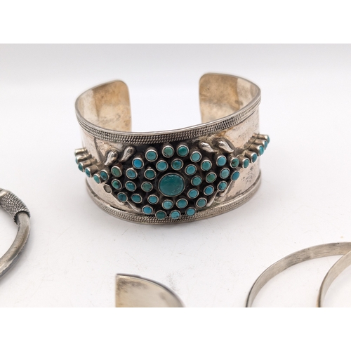 33 - A collection of silver bangles to include examples from Mexico, a Navajo style cuff bracelet set wit... 
