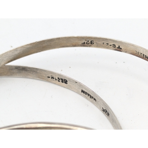 33 - A collection of silver bangles to include examples from Mexico, a Navajo style cuff bracelet set wit... 