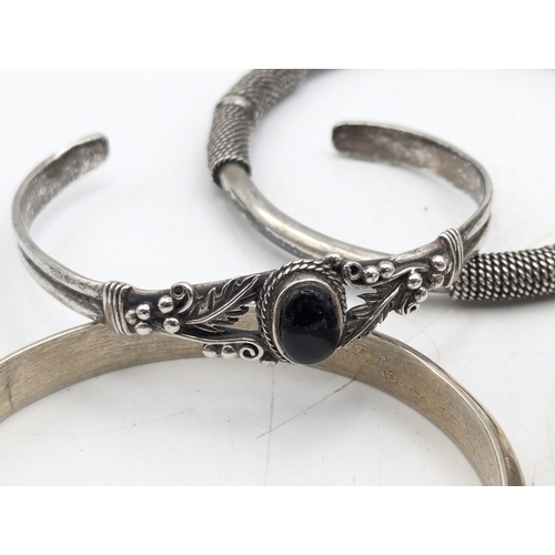 33 - A collection of silver bangles to include examples from Mexico, a Navajo style cuff bracelet set wit... 