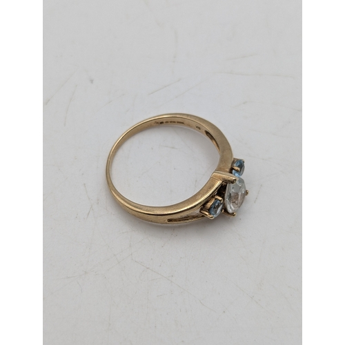 44 - A 9ct yellow gold ring set with a pear cut topaz flanked by two blue claw set topaz stones, size N, ... 