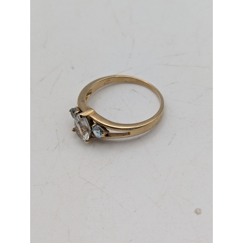 44 - A 9ct yellow gold ring set with a pear cut topaz flanked by two blue claw set topaz stones, size N, ... 