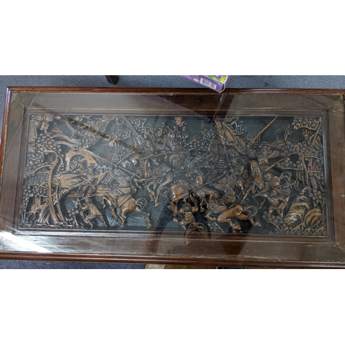 29 - A Chinese carved low table the top depicting a scene of warriors and with a glass top 38cm h x 110.5... 
