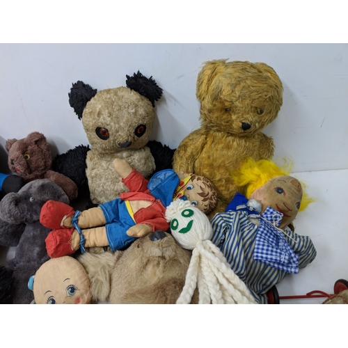 12 - Assorted soft toys and bears to include Golly dolls, a pull along dog on a bike, soft toys some fash... 