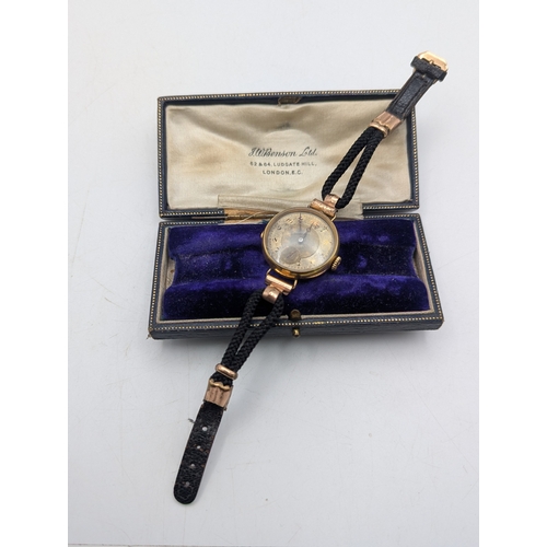 27 - An early to mid 20th century yellow metal cased ladies wrist watch (tested as 18ct gold) on a black ... 