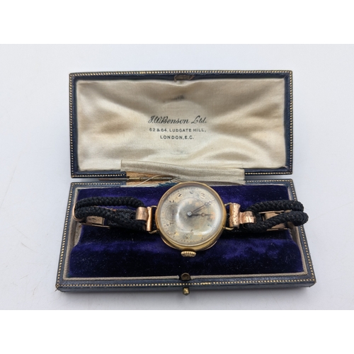 27 - An early to mid 20th century yellow metal cased ladies wrist watch (tested as 18ct gold) on a black ... 