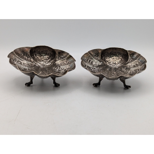 49 - A pair of white metal Indian shell shaped bonbon dishes with embossed and engraved decoration depict... 