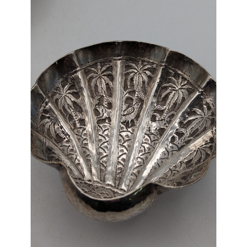 49 - A pair of white metal Indian shell shaped bonbon dishes with embossed and engraved decoration depict... 