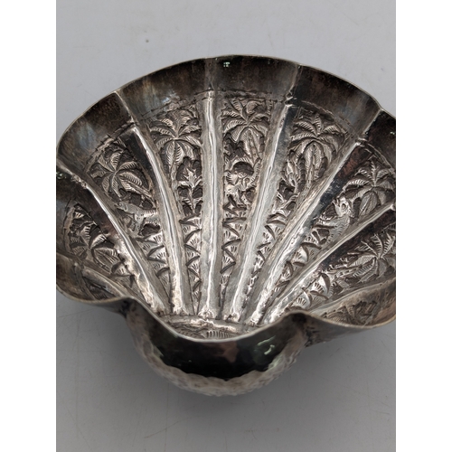 49 - A pair of white metal Indian shell shaped bonbon dishes with embossed and engraved decoration depict... 