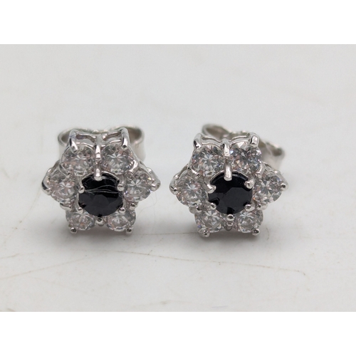 8 - A pair of 18ct white gold earrings fashioned as flower heads set with central sapphires surrounded b... 