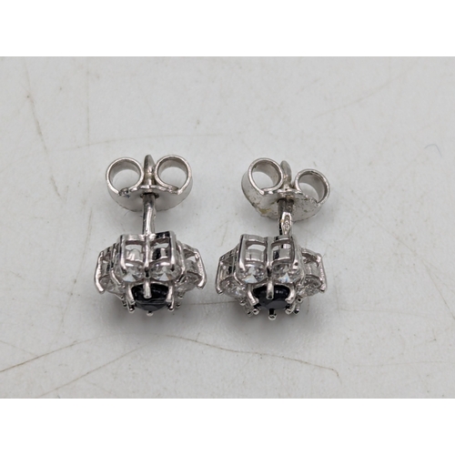 8 - A pair of 18ct white gold earrings fashioned as flower heads set with central sapphires surrounded b... 