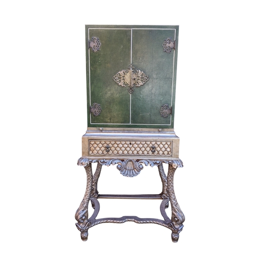An Asprey & Co bar cabinet on stand, circa 1920, the top clad in green shagreen and ivory borders, applied with pierced metal mounts, opening to reveal slide out drawers, above a silver finished frieze drawer and mirrored slide, raised on a carved stand with shell motif and dolphin form legs, 127cm high x 67cm wide
Ivory Submission reference: KT3QNLTE
If there is no condition report shown, please request