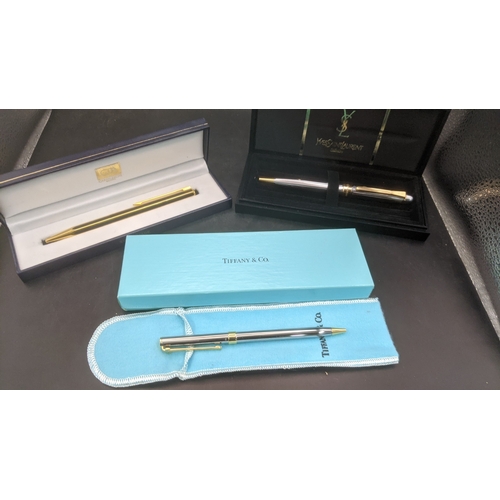 12 - Boxed writing equipment to include a Caran D'ache gold plated ballpoint pen, an Yves Saint Laurent c... 