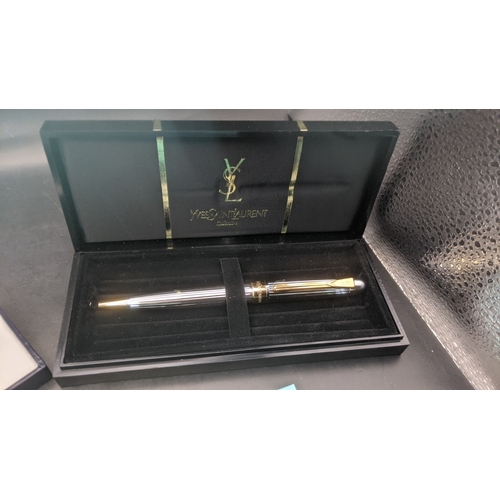 12 - Boxed writing equipment to include a Caran D'ache gold plated ballpoint pen, an Yves Saint Laurent c... 