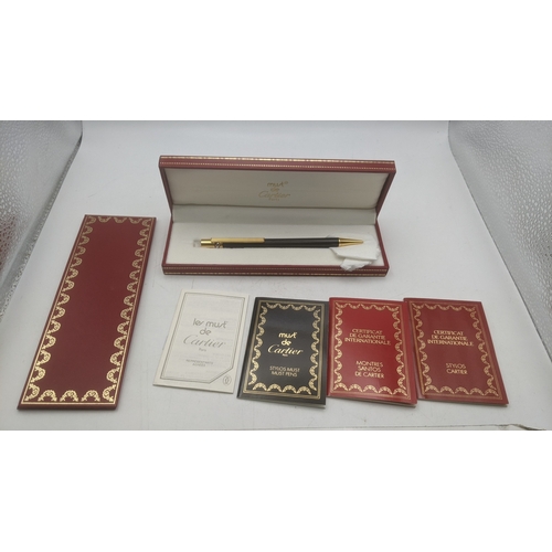 39 - A boxed Must de Cartier Trinity ballpoint pen with a black lacquer body with guarantees and user gui... 