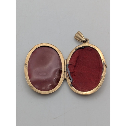 10 - A 9ct yellow gold oval shaped locket with engraved decoration to the centre depicting a butterfly an... 