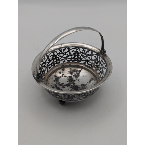 24 - A silver basket having floral pierced decoration in circular form on three ball feet and swing handl... 
