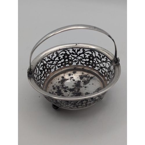 24 - A silver basket having floral pierced decoration in circular form on three ball feet and swing handl... 