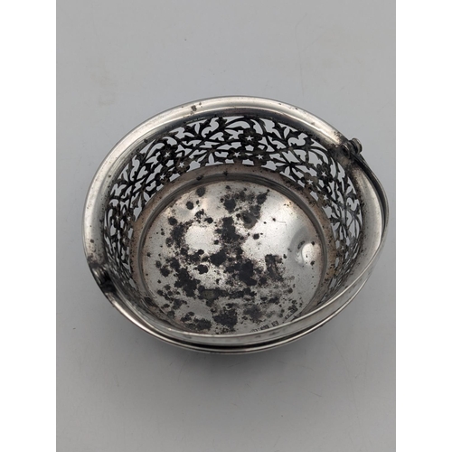 24 - A silver basket having floral pierced decoration in circular form on three ball feet and swing handl... 