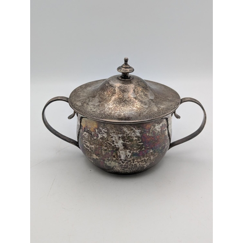 52 - A silver sugar bowl with hammered decoration c-scroll twin handles and lid with tiered finial, hallm... 