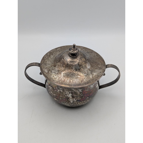 52 - A silver sugar bowl with hammered decoration c-scroll twin handles and lid with tiered finial, hallm... 