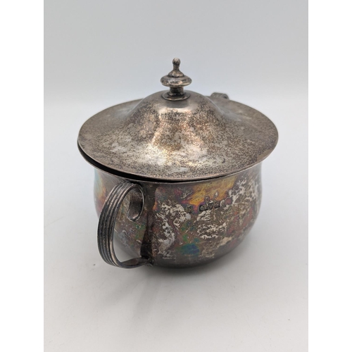 52 - A silver sugar bowl with hammered decoration c-scroll twin handles and lid with tiered finial, hallm... 