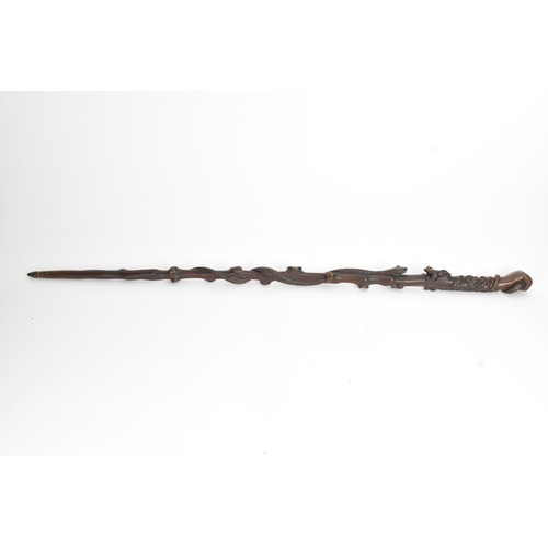 11 - A late 19th/early 20th century hardwood carved walking stick, the shaft carved in relief with a clim... 