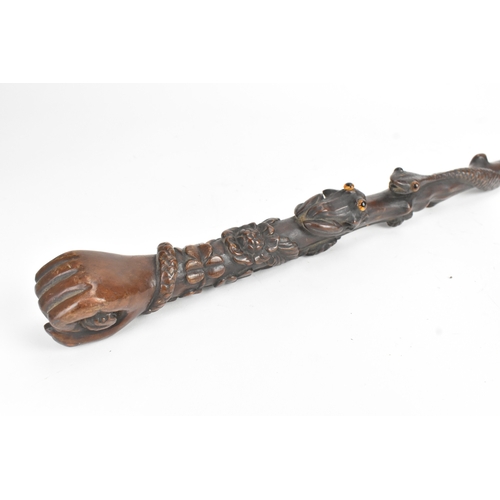 11 - A late 19th/early 20th century hardwood carved walking stick, the shaft carved in relief with a clim... 