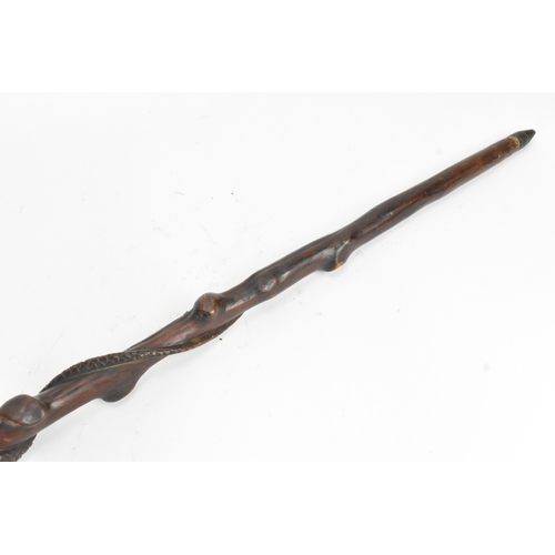 11 - A late 19th/early 20th century hardwood carved walking stick, the shaft carved in relief with a clim... 