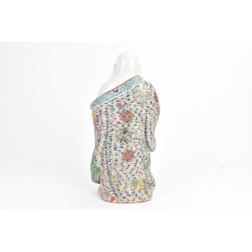 15 - A Chinese famille rose porcelain figure of Buddha, modelled standing holding a cup, his robe decorat... 