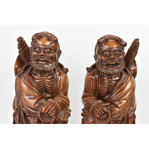 36 - A pair of Chinese hardwood carved figures of immortals, 20th century, each modelled standing holding... 