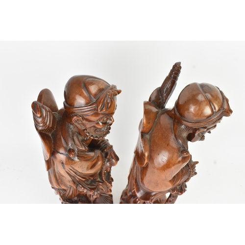 36 - A pair of Chinese hardwood carved figures of immortals, 20th century, each modelled standing holding... 