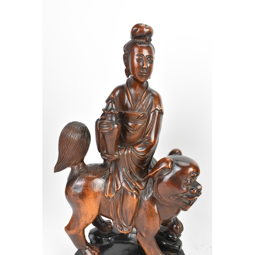 37 - Two Chinese hardwood carved figures, 20th century, one modelled seated upon a shi-shi lion and holdi... 