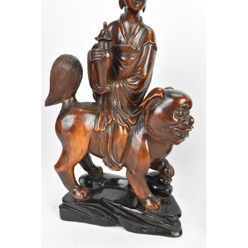 37 - Two Chinese hardwood carved figures, 20th century, one modelled seated upon a shi-shi lion and holdi... 