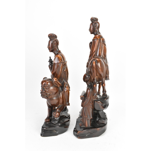 37 - Two Chinese hardwood carved figures, 20th century, one modelled seated upon a shi-shi lion and holdi... 