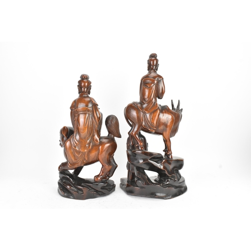 37 - Two Chinese hardwood carved figures, 20th century, one modelled seated upon a shi-shi lion and holdi... 