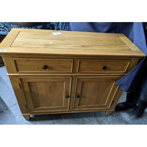 268 - A contemporary light wood side chest of two short drawers above twin cupboard doors, on short taperi... 