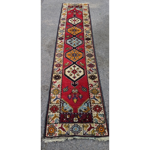 198 - A handwoven Turkish runner with cream blue and orange central medallions with a cream stylized borde... 