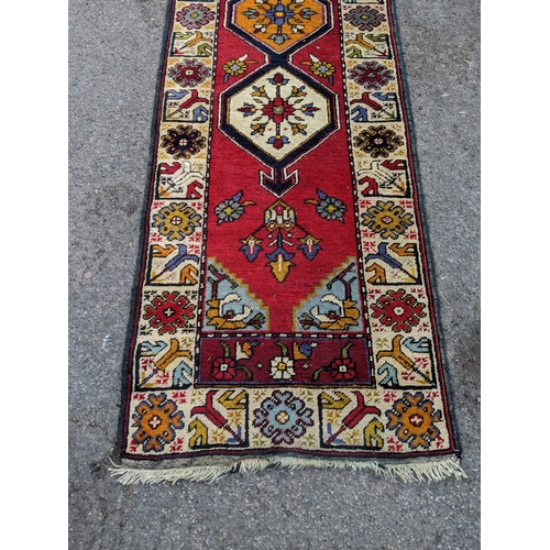 198 - A handwoven Turkish runner with cream blue and orange central medallions with a cream stylized borde... 