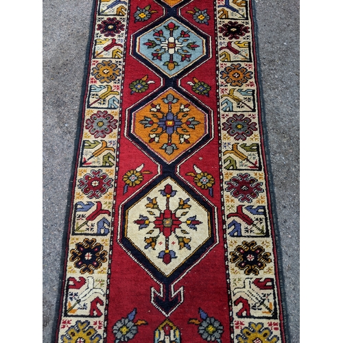 198 - A handwoven Turkish runner with cream blue and orange central medallions with a cream stylized borde... 