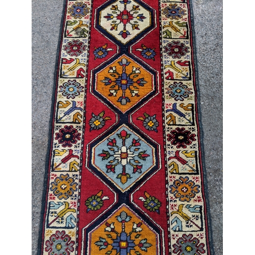 198 - A handwoven Turkish runner with cream blue and orange central medallions with a cream stylized borde... 