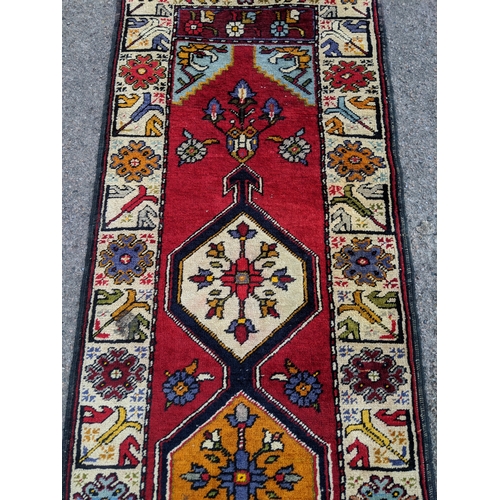 198 - A handwoven Turkish runner with cream blue and orange central medallions with a cream stylized borde... 